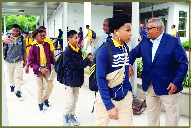 Photo of men in suits escorting a group of youth in school blazers